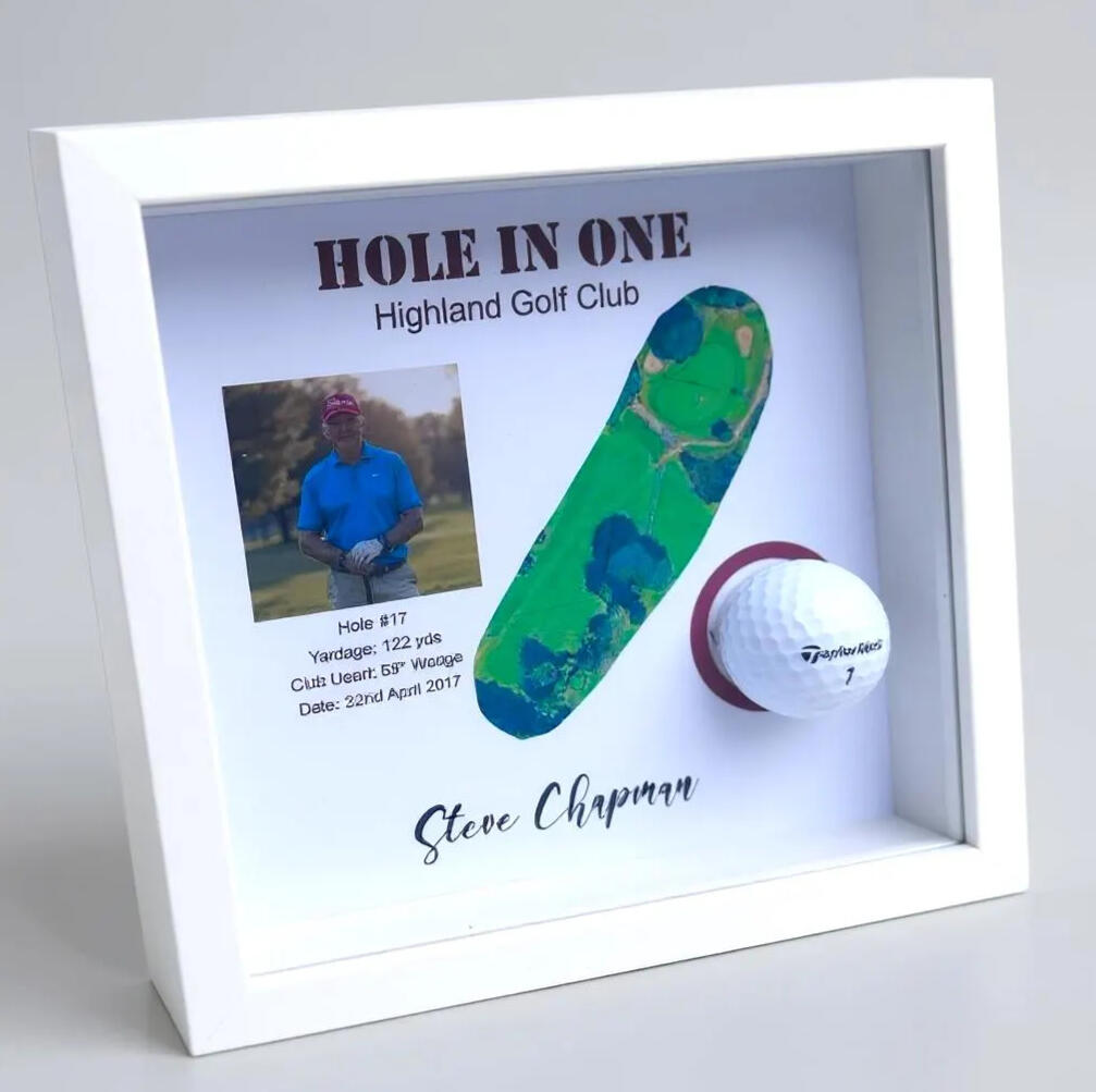 White frame with a printed background of a golf hole and a golfers image with a cutout in it holding a golf ball.